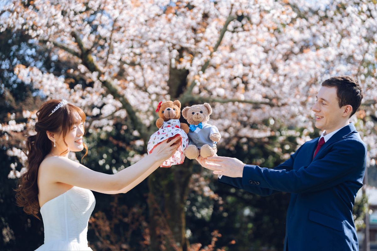 This couple held plush toys against a stunning backdrop of sakura trees during their pre-wedding photoshoot in Japan