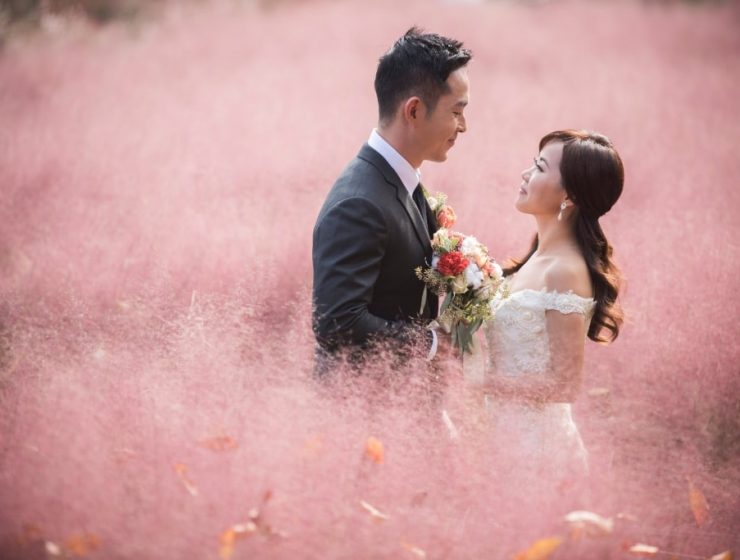 wedding couple with bouquet in pink field