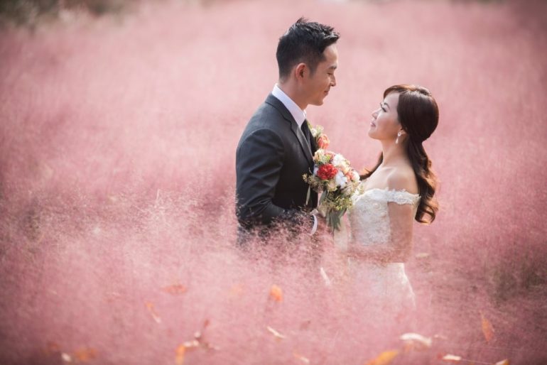 wedding couple with bouquet in pink field