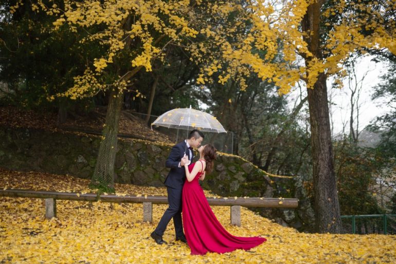 bride in red dress among yellow autumn foliage