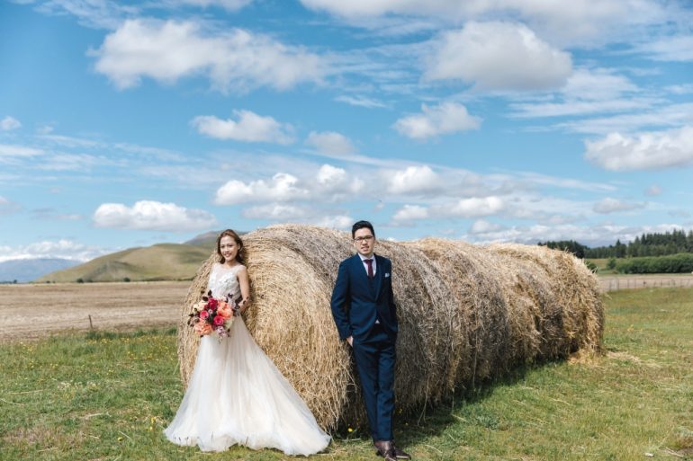 bride in white flowy dress with hay rolls in new zealand