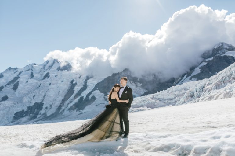 bride in long black gown on snow mountain
