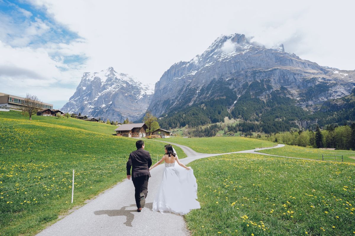Pre-wedding couple running along a scenic road in Grindelwald with the Swiss Alps as the backdrop.