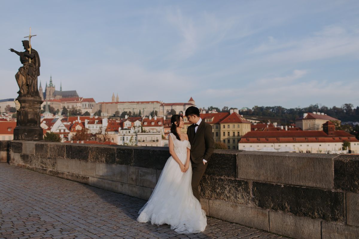 Romantic pre-wedding photo of a couple standing on Charles Bridge in Prague