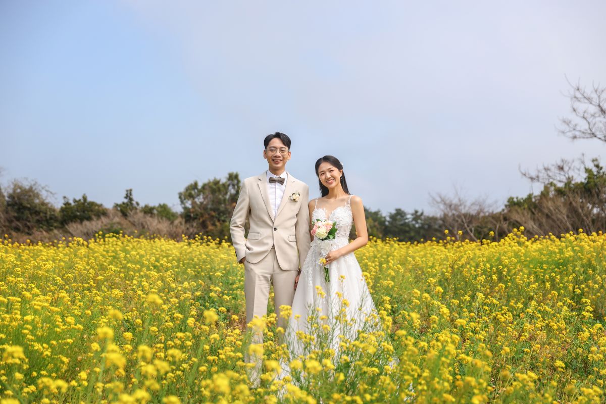Couple posing in vibrant flower field during Jeju pre-wedding photoshoot