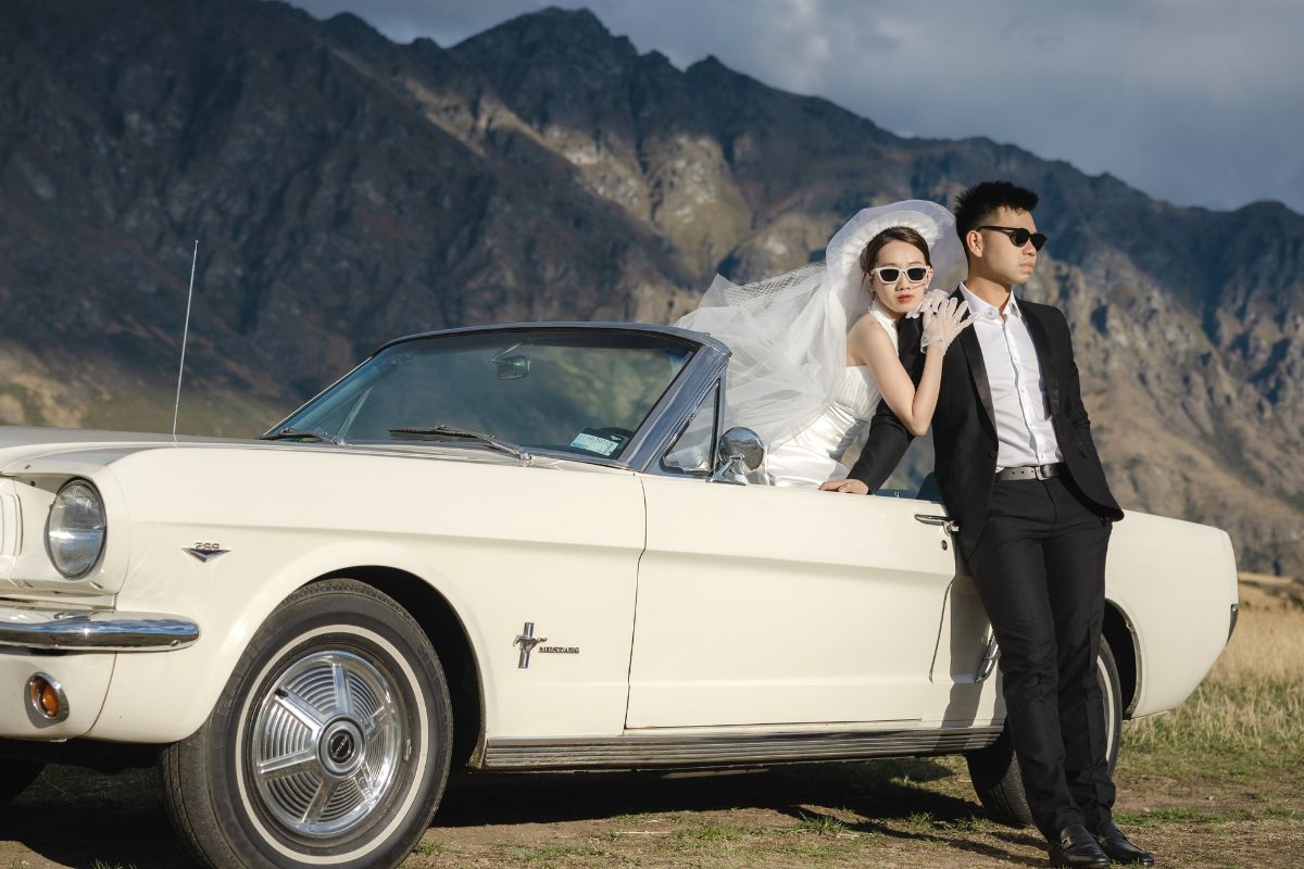Couple posing by a vintage car for their romantic pre-wedding photoshoot in scenic New Zealand