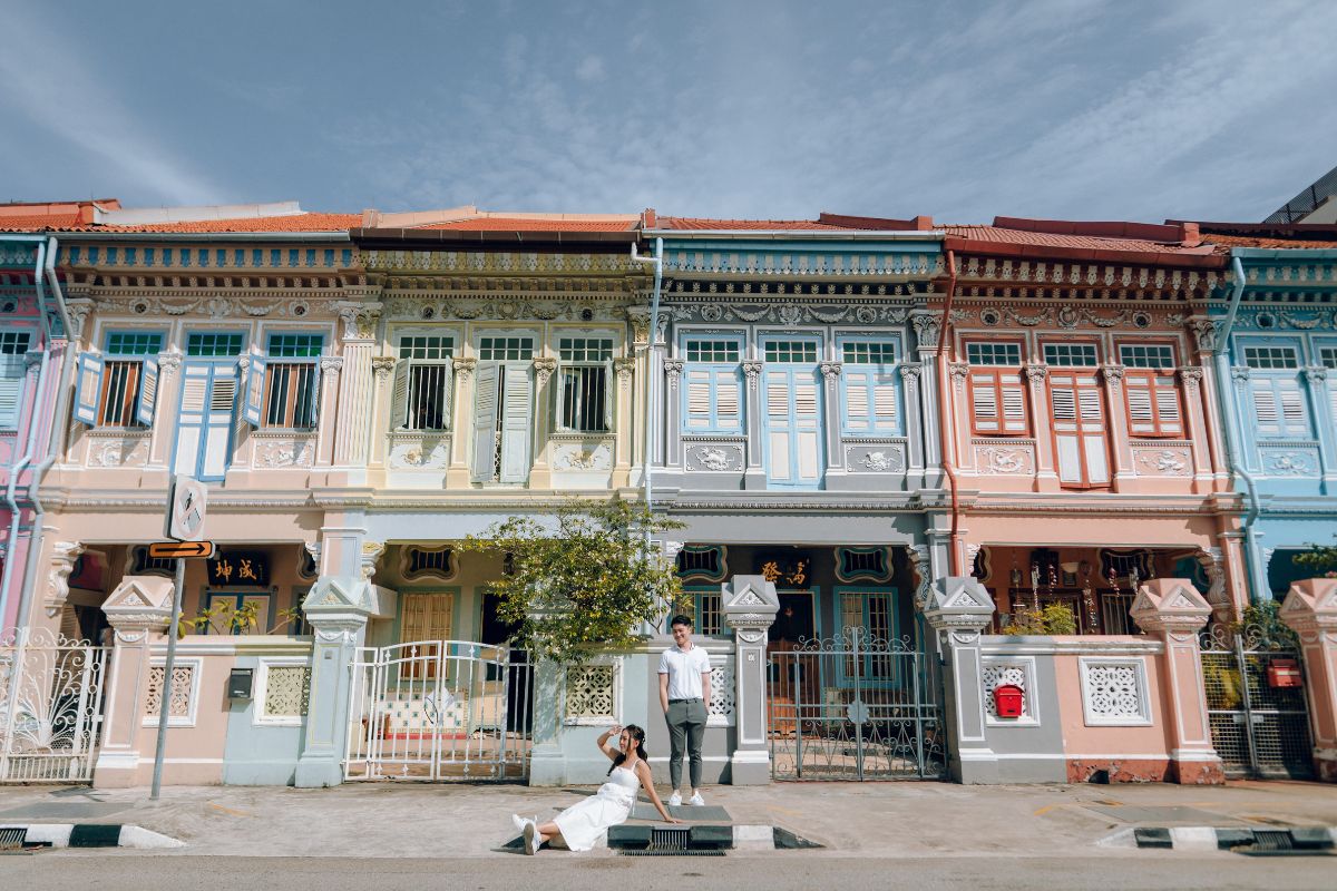 Couple posing for pre-wedding photos in front of colourful Peranakan shophouses at Joo Chiat, Singapore.
